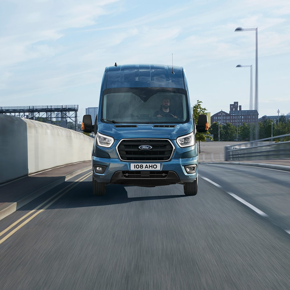 Modrá dodávka Ford Transit jede po víceproudé silnici