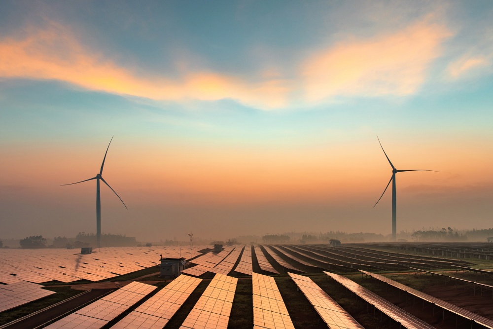 Zdroje obnovitelné energie, včetně větrných turbín a solárních panelů, zobrazené při západu slunce.