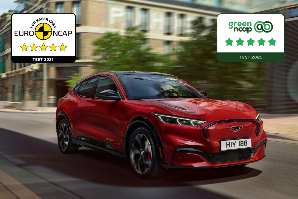 Červený Mustang Mach-E jedoucí po silnici s vyobrazenými logy bezpečnostních ocenění NCAP.