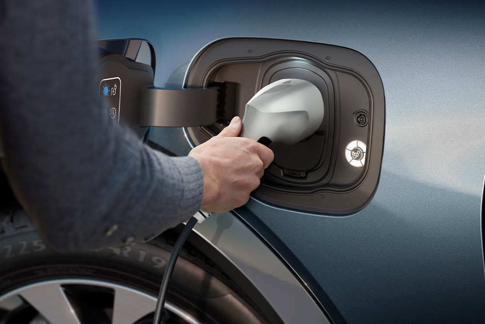 Detailní pohled na člověka, který nabíjí elektromobil Ford.