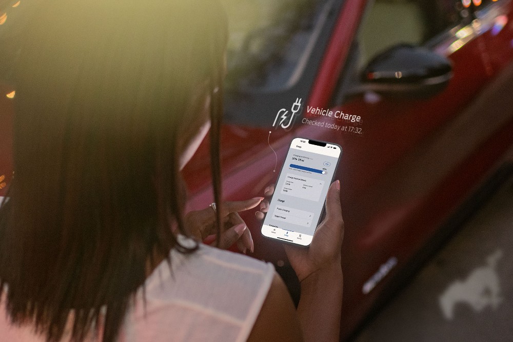 Osoba používá FordPass u červeného Fordu Mustang Mach-E