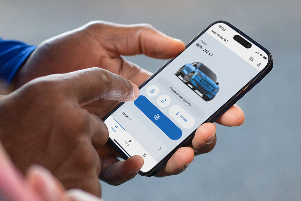 Detailní záběr na iPhone zobrazující aplikaci Ford s grafikou Ford Mustang Mach-E a několika tlačítky aplikace.