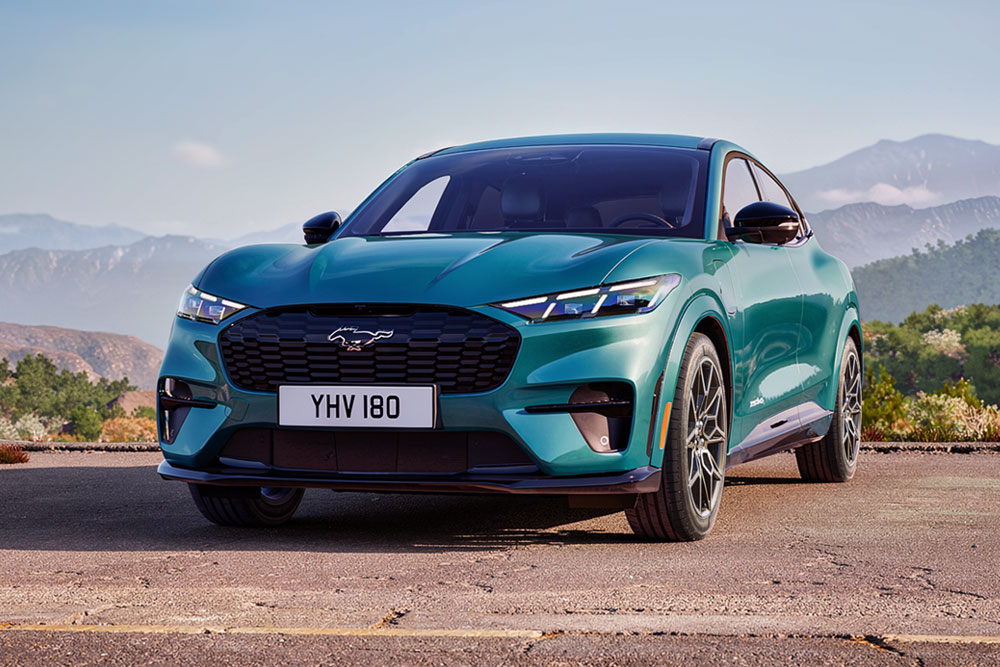 Detailní záběr na stylový Ford Mustang Mach-E GT, s jedinečným znakem GT na designové voštinové přední mřížce.