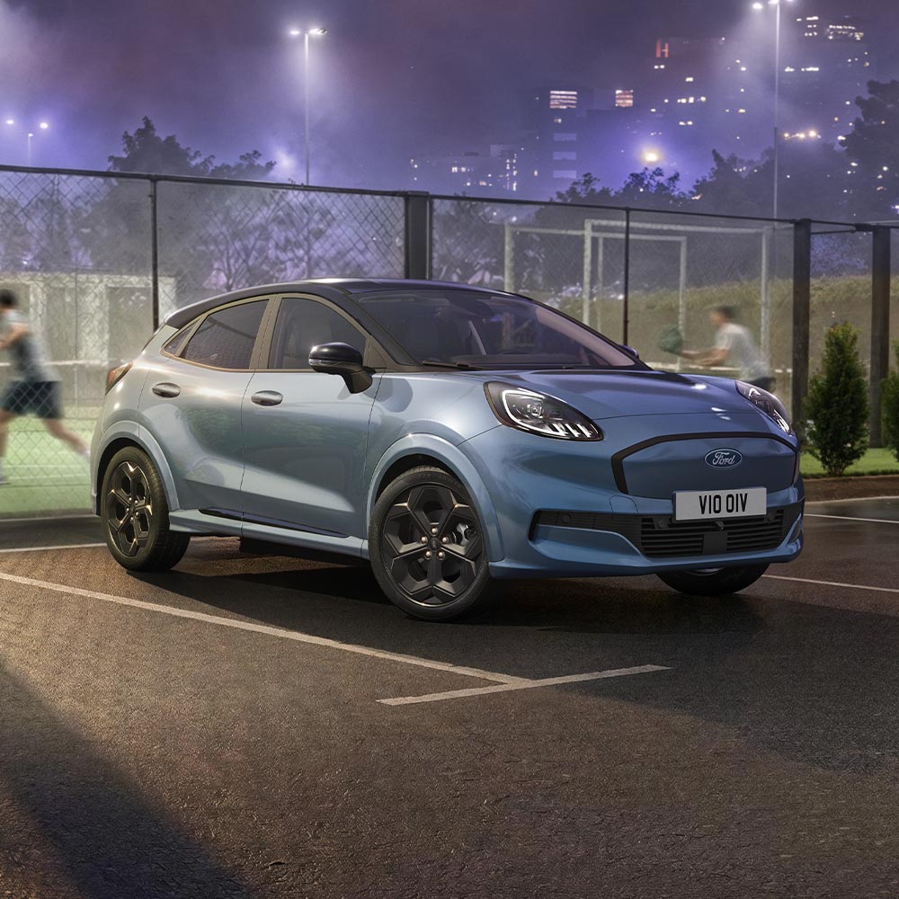 Vůz limitované edice Vapour Blue Ford Puma Gen-E s technologií BlueCruise zaparkovaný vedle venkovního padelového kurtu.