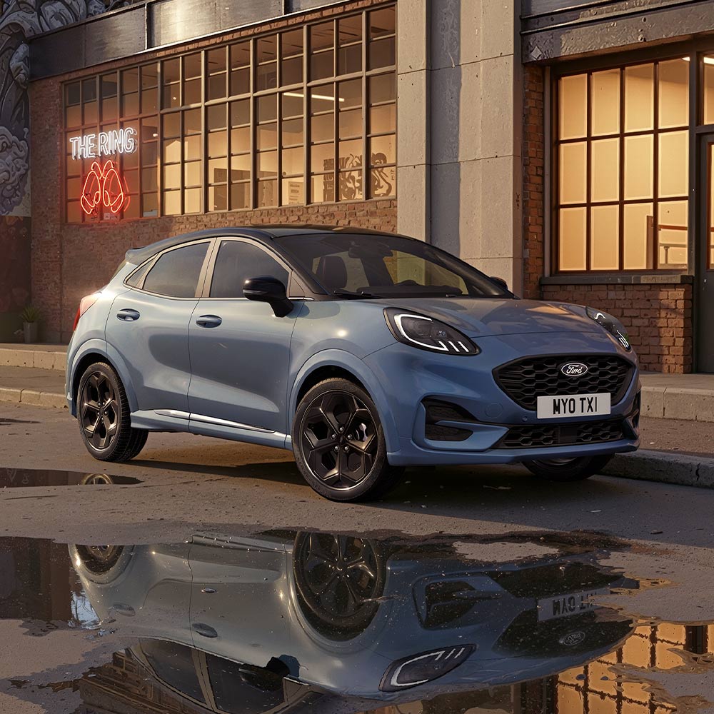 Limitovaná edice Vapour Blue Ford Puma parkující v noci na slabě osvětlené městské ulici.