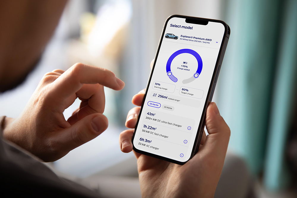 Osoba drží chytrý telefon s aplikací Ford zobrazující rozhraní průběhu nabíjení elektromobilu.