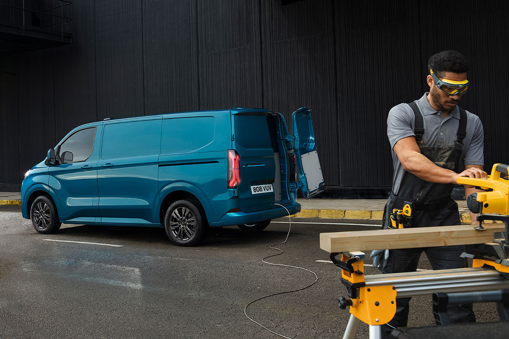 Modrá elektrická dodávka Ford E-Transit Custom a osoba používající elektrické nářadí.