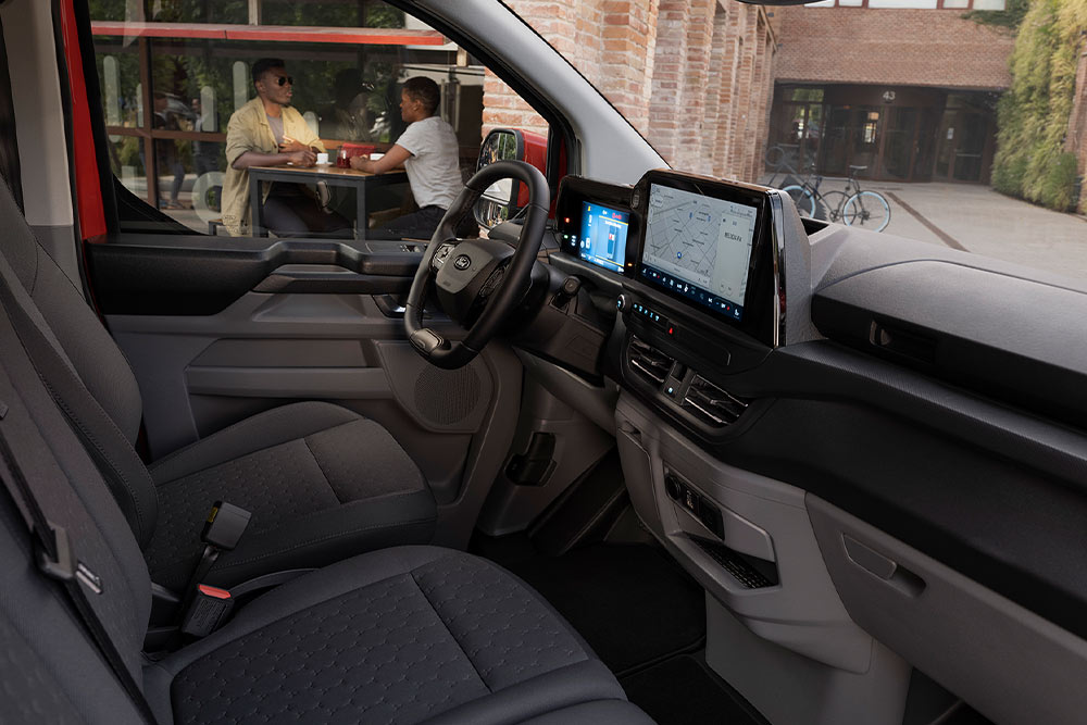 Osoba sedící na sedadle řidiče červené dodávky Ford Transit Custom.