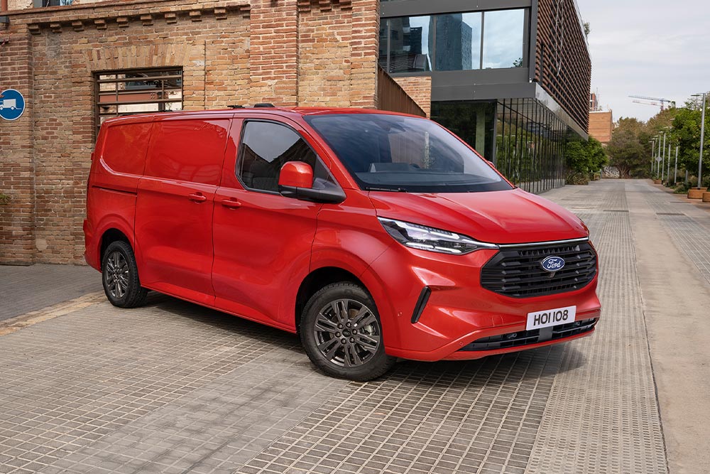 Kurýr nakládá balíky do červeného vozu Ford Transit Custom.