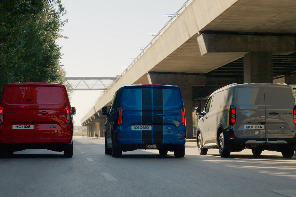 Tři dodávky Ford Transit Custom jedoucí po silnici.