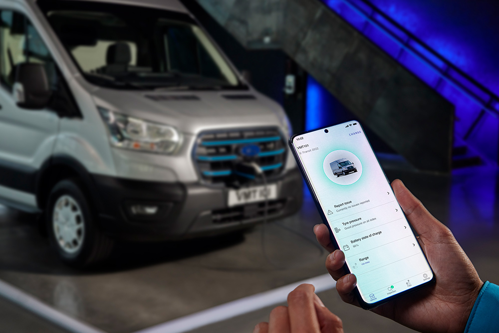 Telefon se zapnutou aplikací Ford app, v pozadí nabíjející se Ford E-Transit Van. 