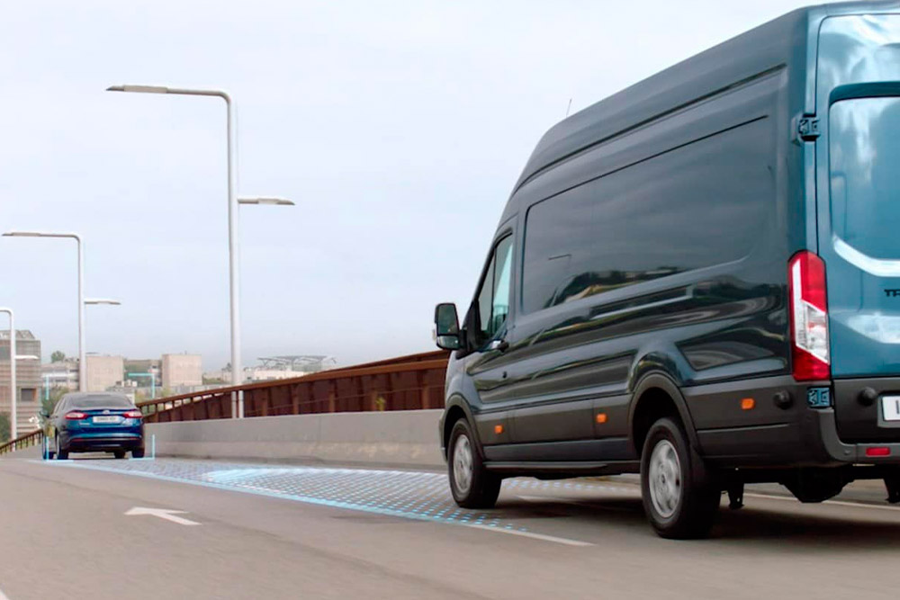 Modrý Ford Transit Van s modrými čarami na silnici znázorňujícími použití pokročilých asistenčních systémů.